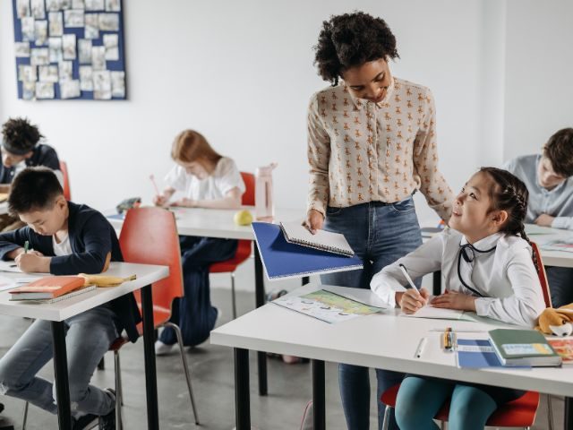Black female teacher discussing paper with student