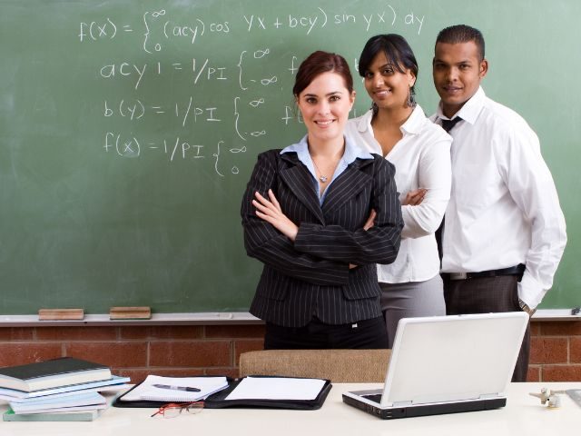 three culturally diverse teachers standing in front of a chalkboard
