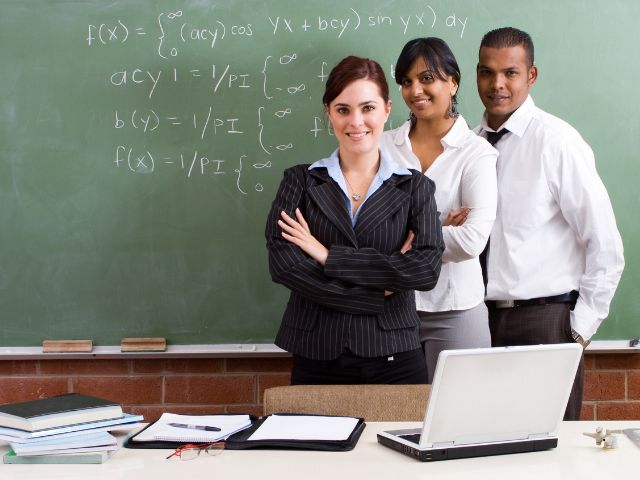 three culturally diverse teachers standing in front of a chalkboard